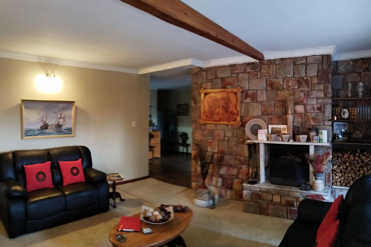Spacious living room featuring a prominent stone fireplace, exposed timber ceiling beam, and classic coving detail.