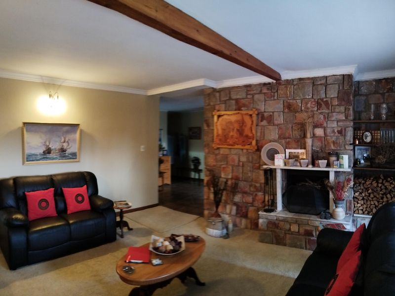 Spacious living room featuring a prominent stone fireplace, exposed timber ceiling beam, and classic coving detail.