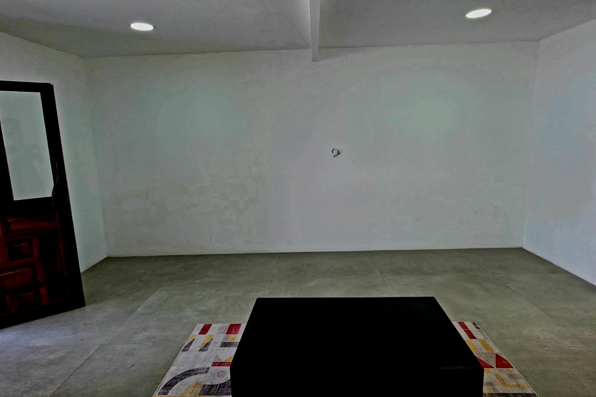 An empty living room featuring tiled flooring, recessed downlights, and a timber door, presenting a blank canvas for interior design.
