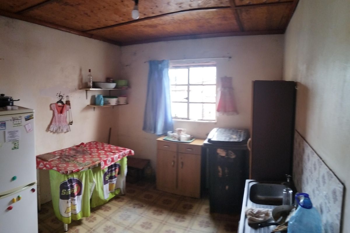 A dated kitchen area featuring a wooden ceiling, tiled flooring, and basic sink installation, requiring significant cosmetic updates and modernization.
