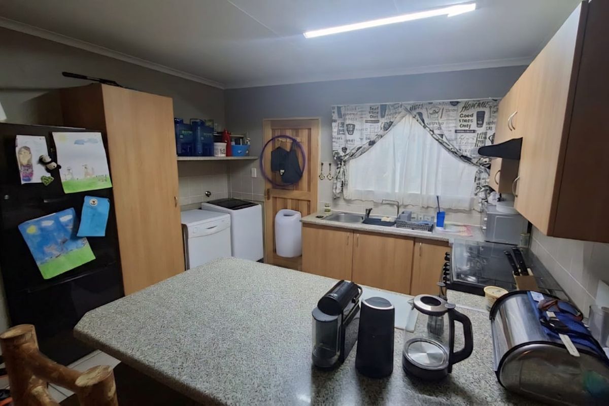 Functional kitchen featuring laminate countertops, wooden cabinetry, and a dedicated laundry area with plumbing connections for appliances.