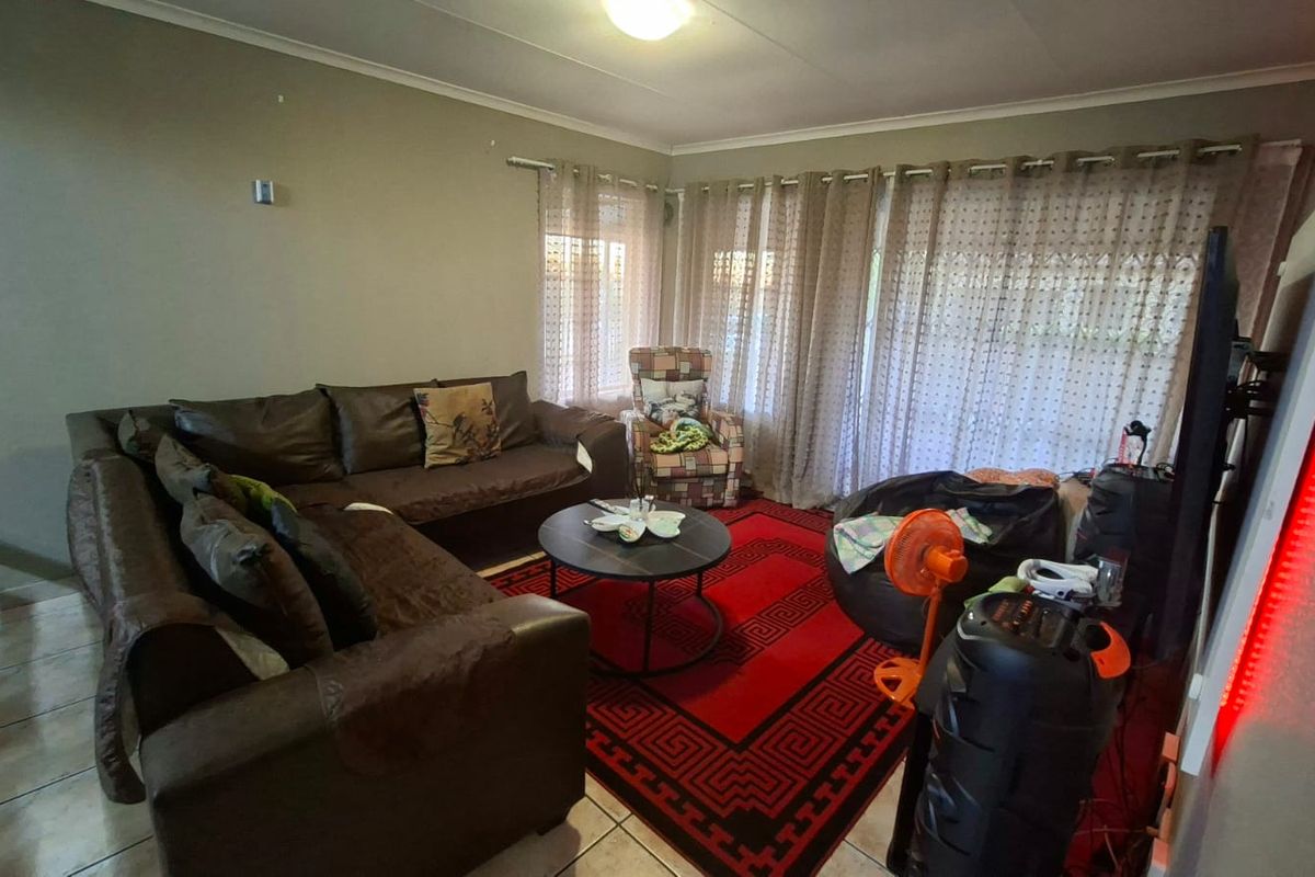 A living room featuring tiled flooring and large windows with curtain tracks, providing a functional and comfortable space for relaxation.