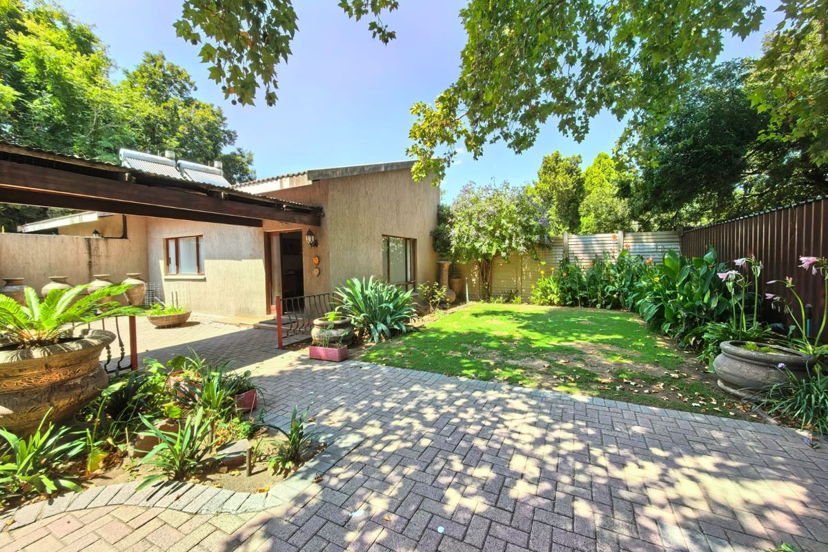 A private rear garden featuring a paved patio area, established landscaping, and a covered outdoor space adjacent to the main dwelling.