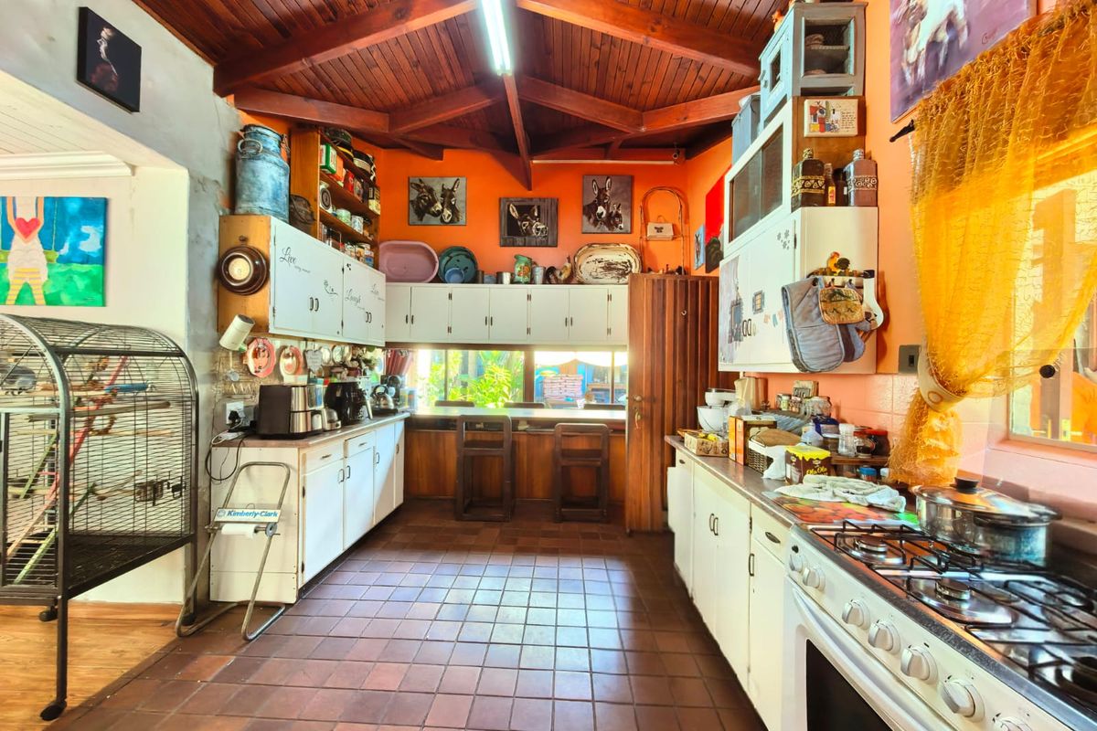 Spacious kitchen featuring a vaulted timber ceiling, extensive built-in cabinetry, tiled flooring, and a gas stove with integrated oven.
