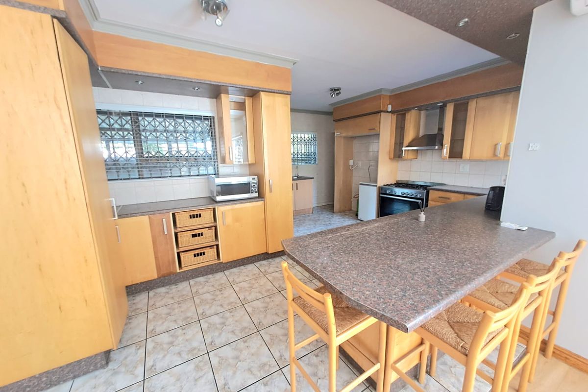 Spacious kitchen featuring light wood cabinetry, granite-look countertops, a breakfast bar, and a built-in oven with extractor fan.