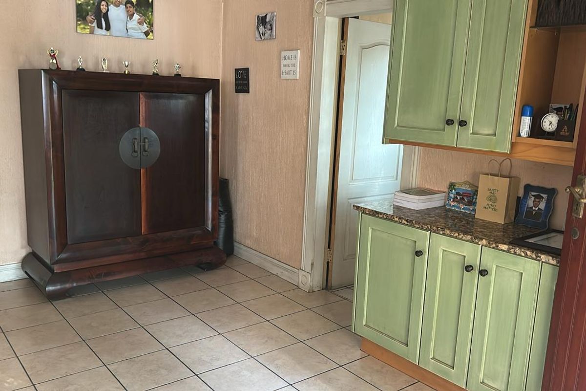 A functional kitchen area featuring green cabinetry, granite-style countertops, and tiled flooring, providing a practical workspace with integrated storage solutions.