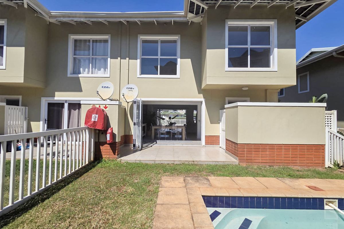 Rear view of a townhouse featuring a private patio, small garden, and swimming pool, with direct access to the open-plan living area.
