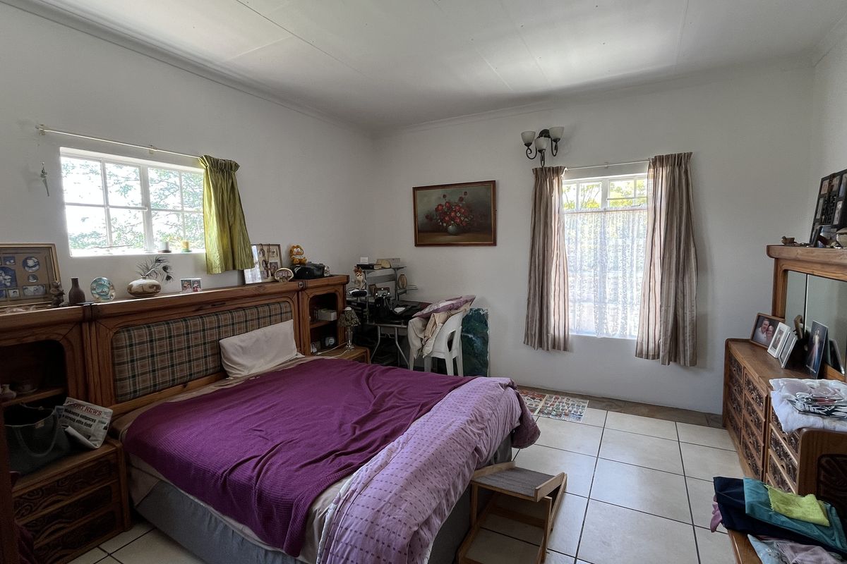 A spacious bedroom featuring tiled flooring, dual windows providing natural light, and built-in wall fixtures.