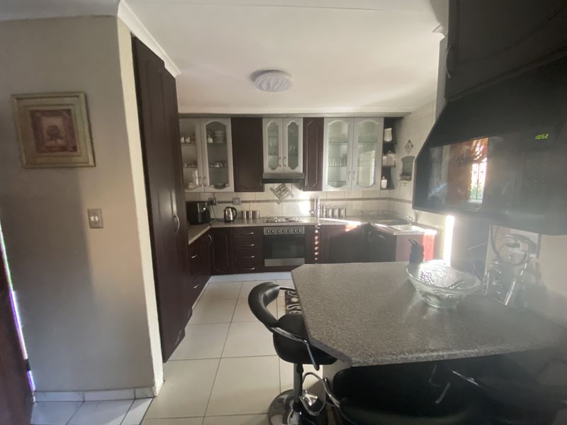 A functional kitchen featuring dark wood cabinetry, tiled flooring, a built-in oven and hob, and a breakfast counter.