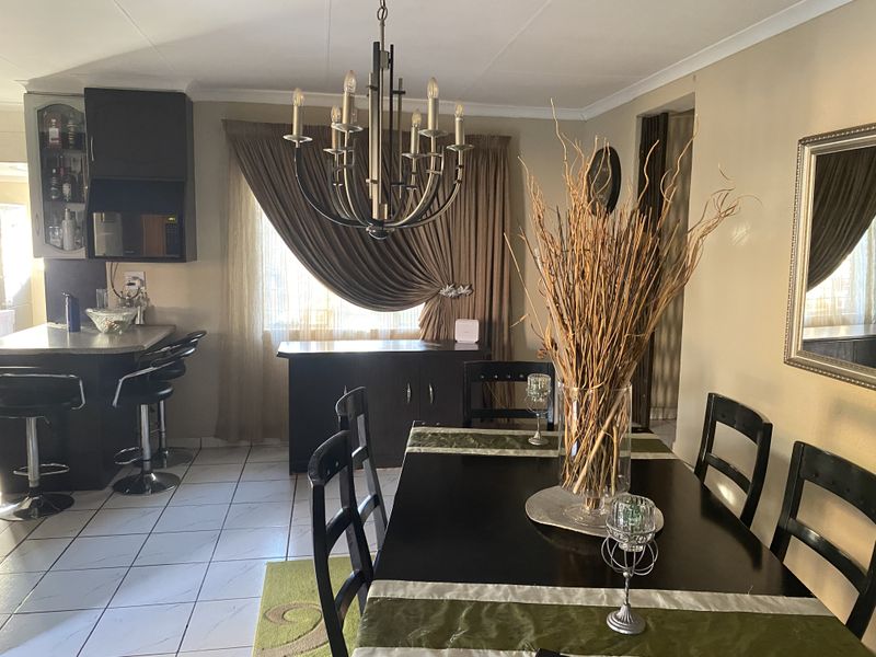 Open plan dining and kitchen area featuring tiled flooring, a breakfast bar, and a decorative chandelier.