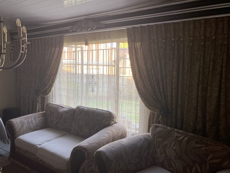 A living room featuring a large window with security bars, decorative crown molding, and a tongue-and-groove ceiling finish.