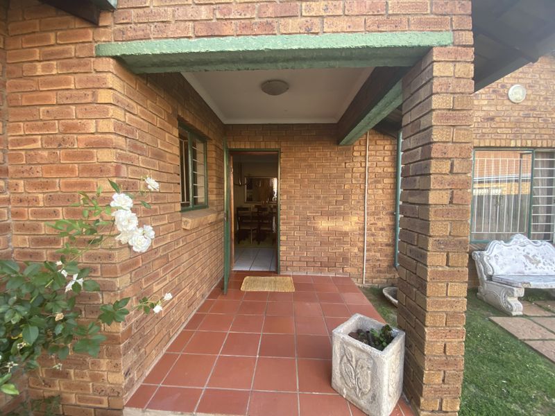 A covered brick entrance porch with terracotta tiled flooring, providing access to the home's interior.