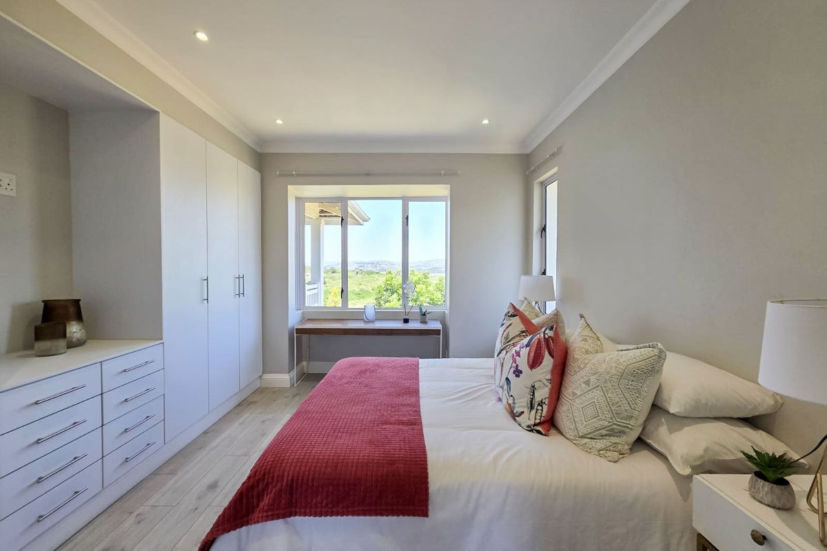 A bright and well-maintained bedroom featuring built-in cabinetry, recessed lighting, and large windows offering pleasant views.
