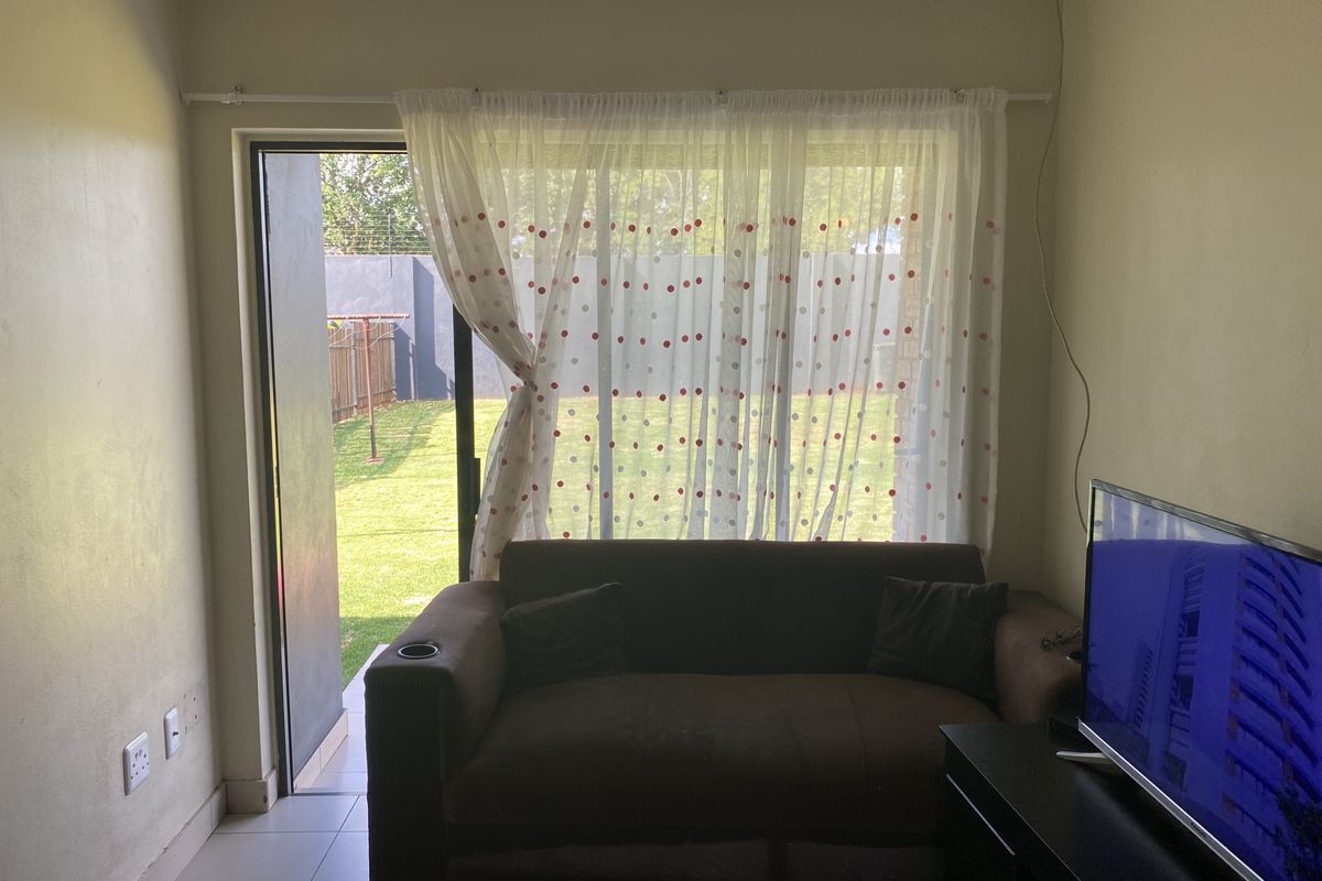 A living room featuring tiled flooring and a sliding glass door providing direct access to the rear garden area.