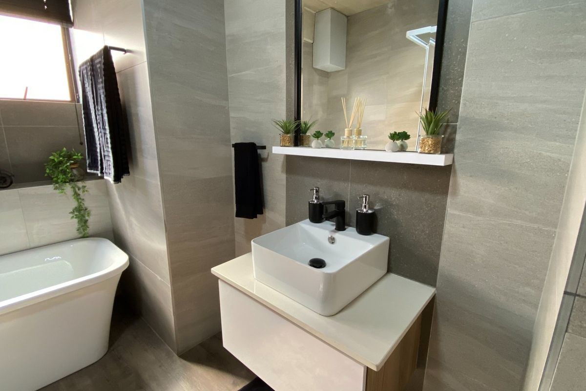 Modern bathroom featuring a contemporary vessel sink vanity, a freestanding bathtub, and neutral large-format wall tiling.
