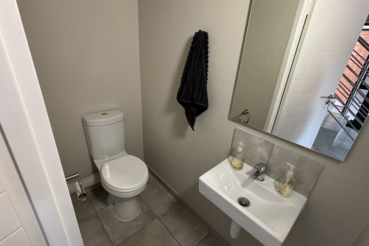 A compact guest powder room featuring a modern wall-mounted basin, a standard toilet, and a wall-mounted mirror.