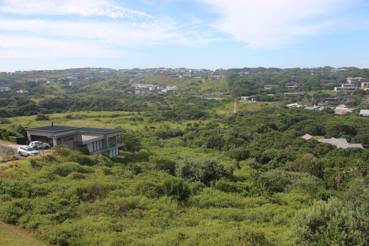 An elevated aerial view showcasing the surrounding landscape, lush greenery, and residential estate development.