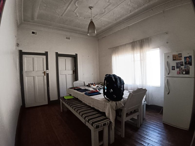 Dining room featuring original hardwood flooring, ornate plaster ceiling details, and classic timber door frames, offering a traditional character space.