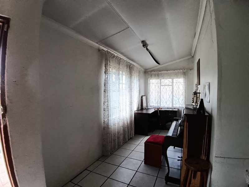 A small bedroom featuring tiled flooring and security bars on the windows, currently used as a multi-purpose space.