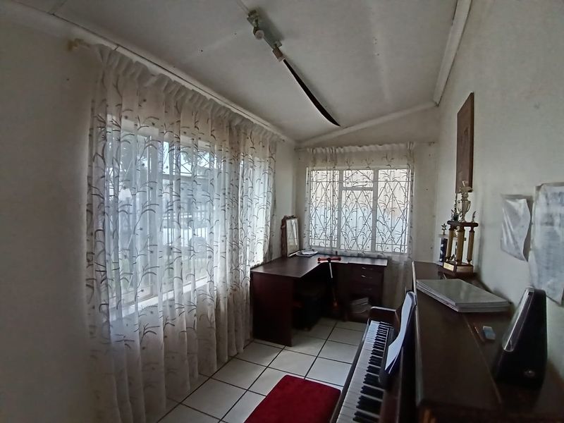 A functional office space featuring tiled flooring and large windows with security bars, offering potential for a refreshed workspace design.