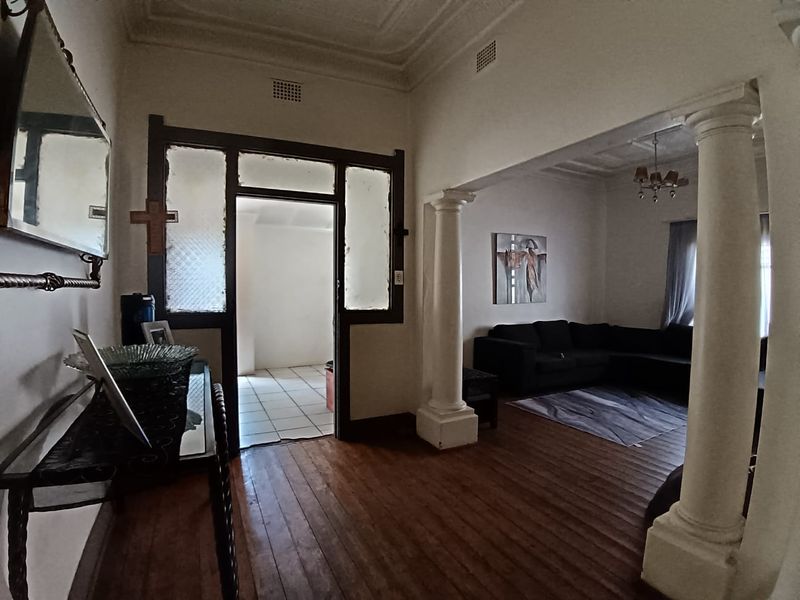 A character-filled hallway featuring original timber flooring, decorative ceiling cornices, and classical columns leading into an open-plan living area.