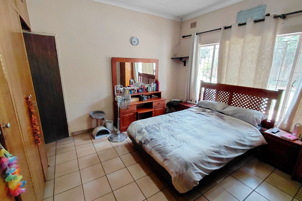 A bedroom featuring tiled flooring, built-in wooden cabinetry, and large windows allowing natural light.