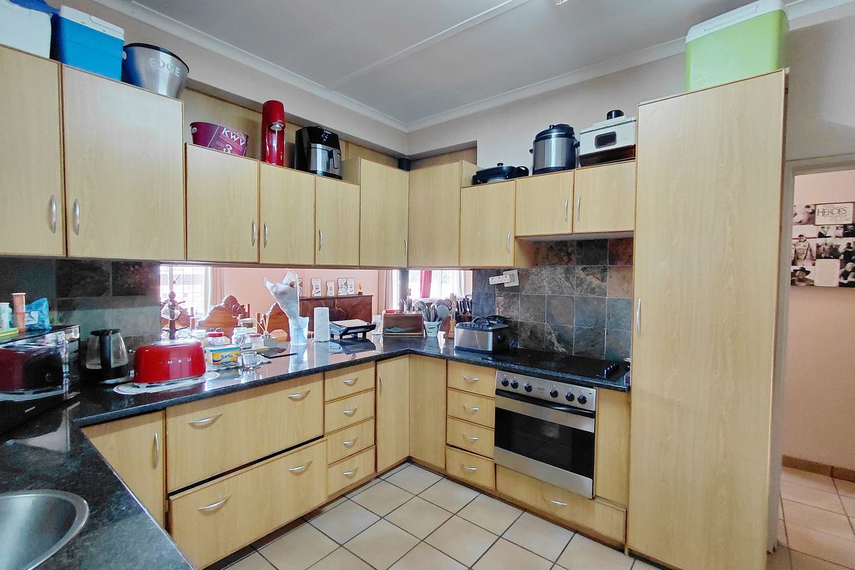 Functional kitchen featuring light wood cabinetry, dark granite countertops, built-in oven, and ceramic floor tiles.