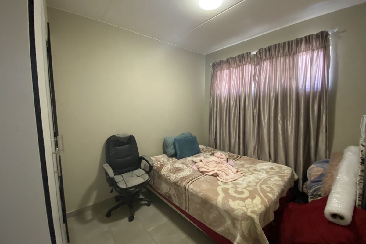 A standard bedroom featuring tiled flooring and built-in cupboard storage.