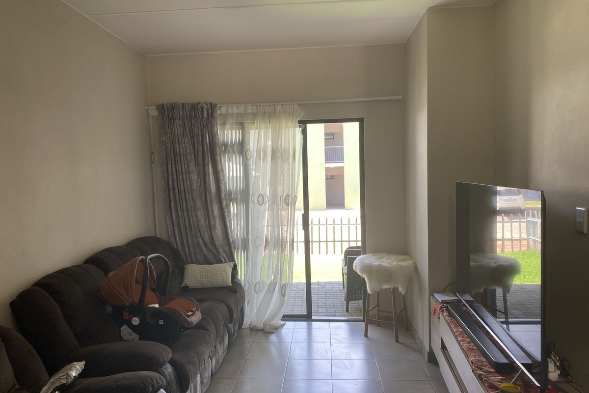 A living room featuring tiled flooring and a sliding glass door providing access to an outdoor patio area.