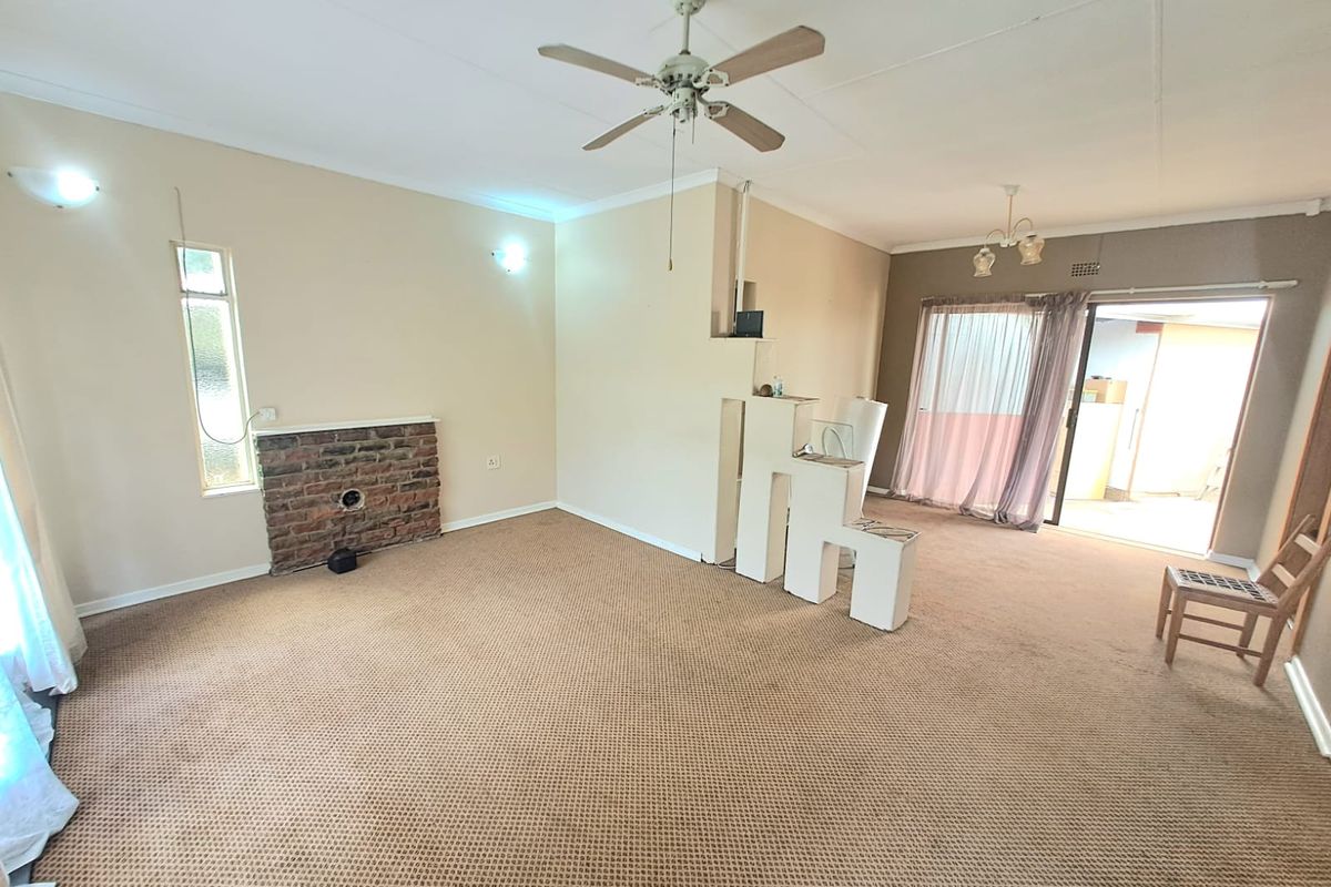 Spacious living area featuring a brick fireplace, ceiling fan, and sliding door access to an outdoor patio space.