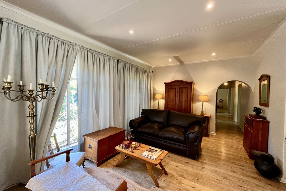 A well-maintained living room featuring light wood-look flooring, recessed ceiling lighting, and an arched doorway leading to the hallway.