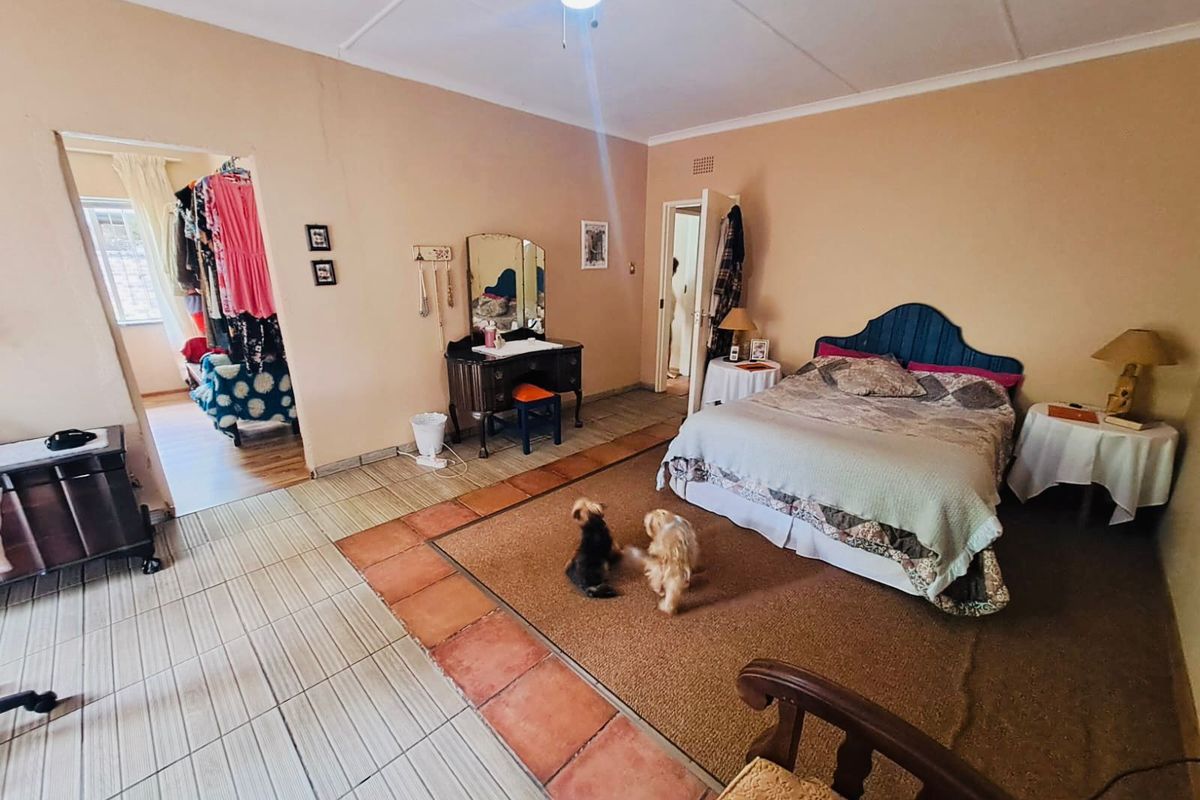 Spacious bedroom featuring tiled flooring with a central carpeted area, providing access to an adjoining dressing room or walk-in closet space.