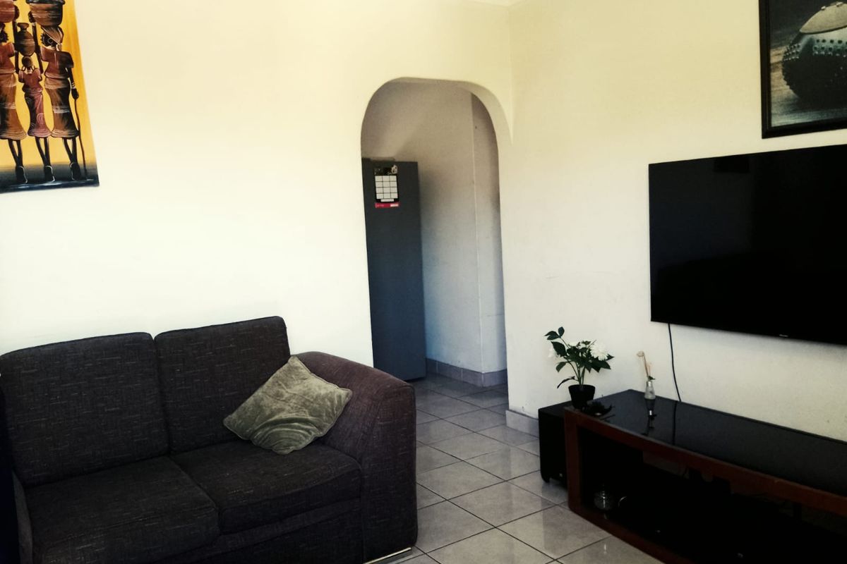 A living room featuring tiled flooring and an arched doorway leading to an adjacent space.
