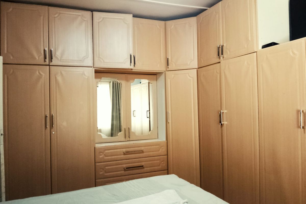 A bedroom featuring extensive built-in wooden cabinetry with integrated storage, drawers, and a central vanity mirror.