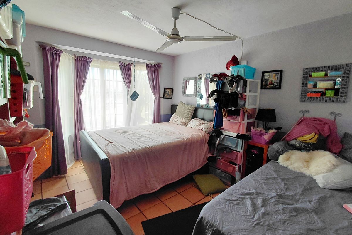 A bedroom featuring tiled flooring, a ceiling fan, and a large window with natural light.