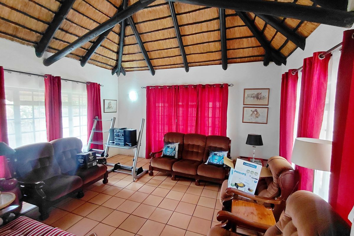 Spacious living room featuring a high vaulted thatched ceiling with exposed timber beams and terracotta floor tiles.