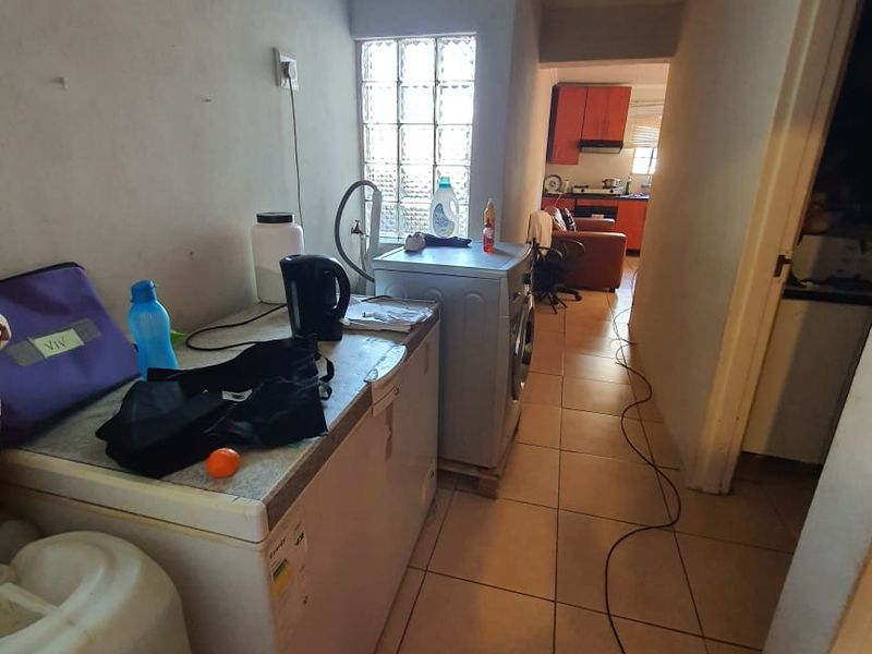 A functional laundry area featuring ceramic floor tiles, a glass block window, and dedicated plumbing connections for appliances.