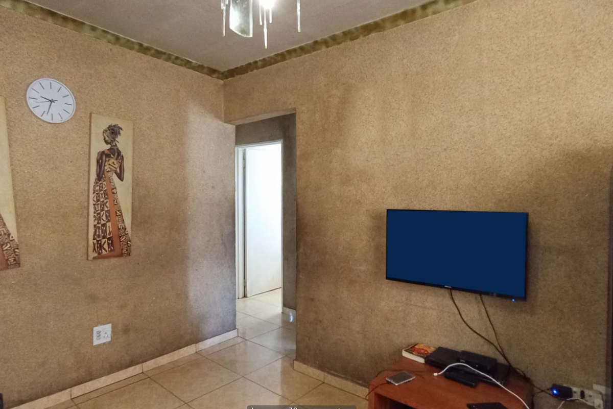 A living room featuring tiled flooring and textured wall finishes with a coved ceiling cornice.