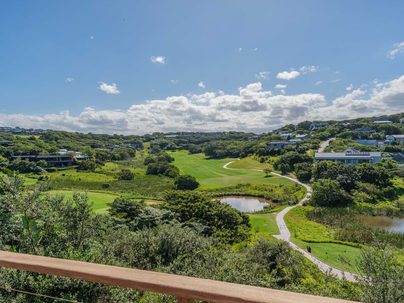 A scenic elevated view overlooking a lush green golf course, natural landscape, and surrounding residential estate.