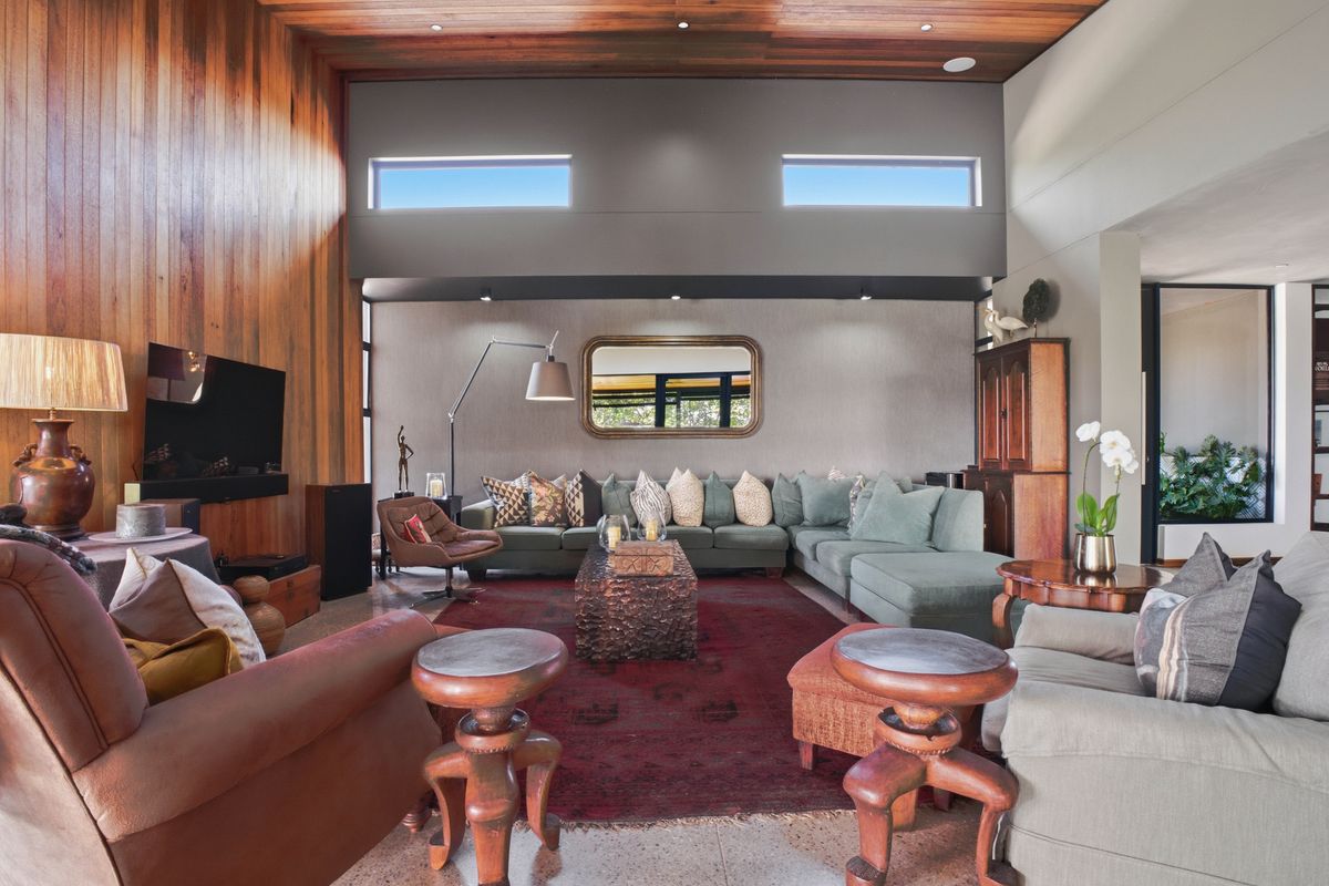 Spacious living room featuring high timber-paneled ceilings, clerestory windows, and polished concrete flooring, creating a warm and inviting atmosphere.