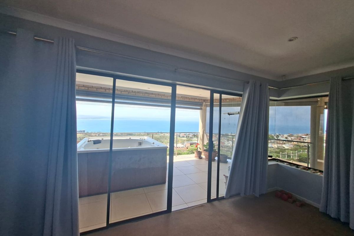 Spacious living area featuring large sliding glass doors that open onto a balcony with a built-in jacuzzi and panoramic ocean views.