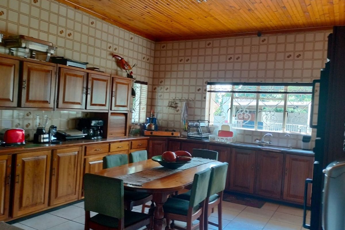 Spacious kitchen featuring timber cabinetry, tiled walls, and a wooden ceiling, with an integrated dining area and ample counter space.