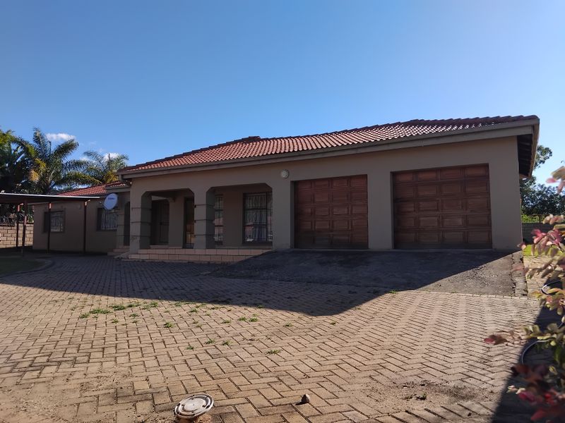 Front exterior view of a single-story house featuring a double garage, paved driveway, and covered entrance porch under a tiled roof.