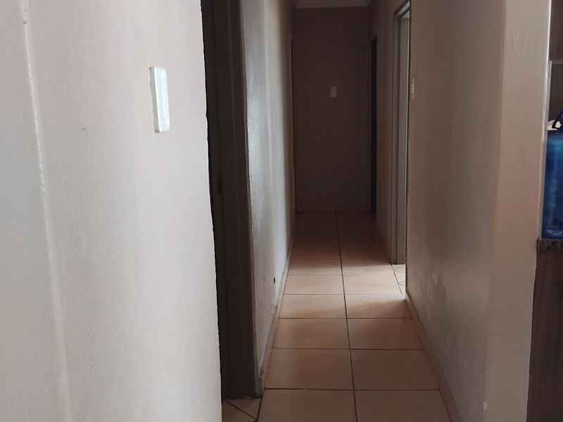 A functional interior hallway featuring neutral wall finishes and tiled flooring, providing access to multiple rooms within the home.