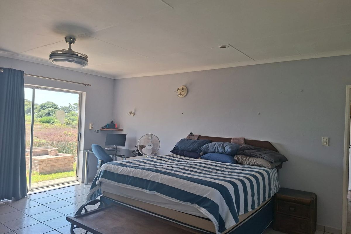 Spacious bedroom featuring tiled flooring, a ceiling fan, and sliding glass doors providing direct access to the outdoor area.