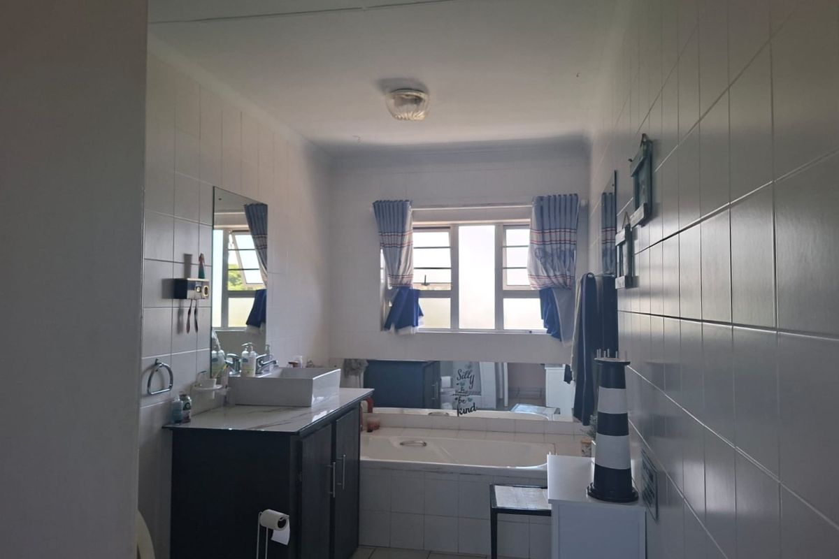 A functional bathroom featuring a built-in vanity with basin, a bathtub, and tiled wall finishes throughout.