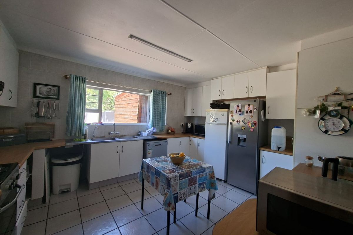 A functional kitchen featuring white cabinetry, laminate countertops, a double basin sink, and tiled flooring, offering a practical layout for daily meal preparation.