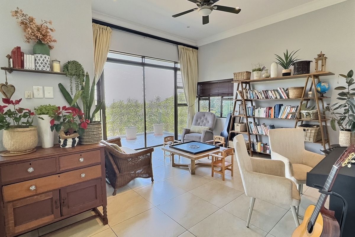 Spacious living area featuring large sliding glass doors leading to an outdoor patio, tiled flooring, and a ceiling fan.