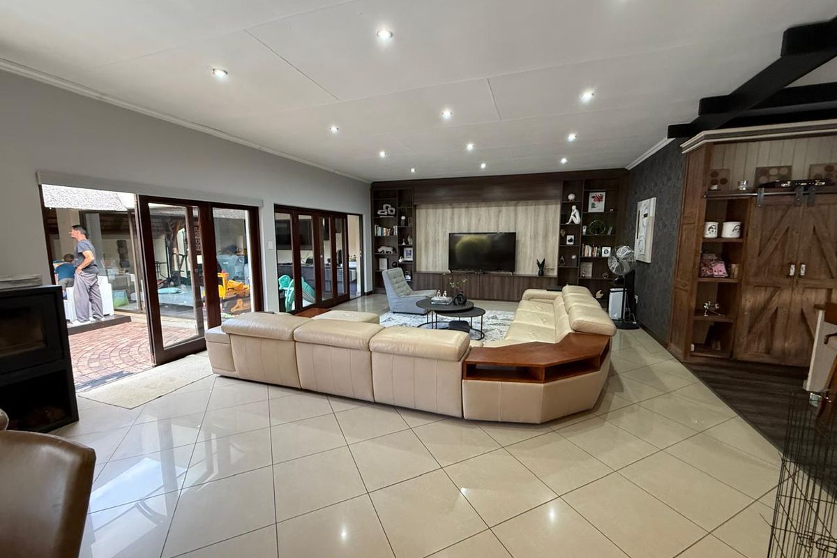 Spacious living room featuring large format floor tiles, recessed ceiling lighting, and custom built-in wooden cabinetry with integrated shelving and media unit.
