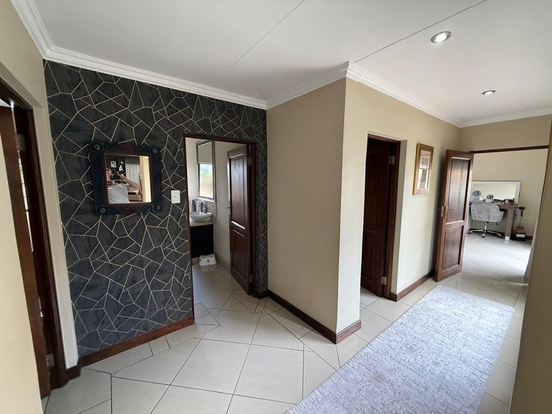 A well-maintained interior hallway featuring tiled flooring, recessed ceiling lighting, and access to multiple rooms with wooden door frames.